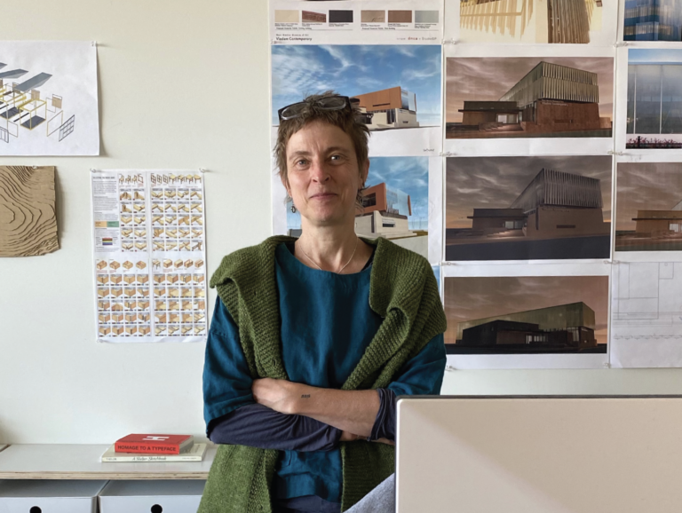 Dierdre Harris, local Santa Fe architect, looks at the camera with her designs behind her